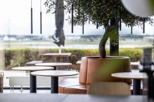 a room with tables and a potted plant and a window at Airport Hotel, Billund in Billund