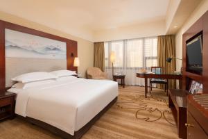 a hotel room with a large white bed and a desk at Shenzhen Sunshine Hotel, Luohu in Shenzhen