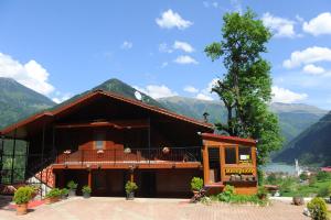 a building with a tree and mountains in the background at Erkonak Pansiyon in Uzungöl