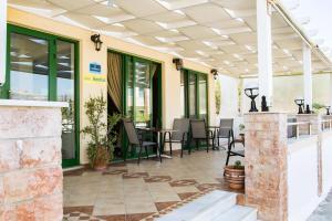 patio ze stołami, krzesłami i oknami w obiekcie Panorama Hotel w mieście Karpatos