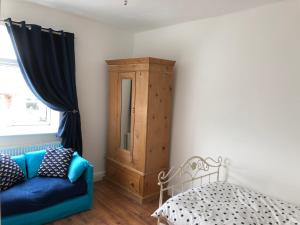 Hilltop Cottage في Renishaw: غرفة بها أريكة زرقاء وخزانة خشبية