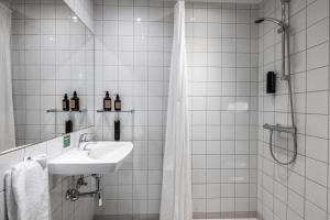 uma casa de banho em azulejos brancos com um lavatório e um chuveiro em Airport Hotel, Billund em Billund