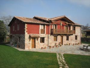 a large brick house with a balcony and a yard at Apartamentos Rurales El Mirador de Cazanes in Cazanes