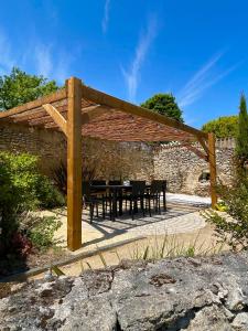 a wooden pergola with a table and chairs under it at Maisons de campagne. Gîte vert. in Brigné