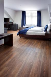 una camera con un grande letto e pavimenti in legno di Schlotzeria Hotel I Café I Eis a Grenzach-Wyhlen