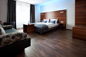 ein Hotelzimmer mit einem Bett und einem Sofa in der Unterkunft Schlotzeria Hotel I Café I Eis in Grenzach-Wyhlen