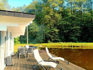 a porch with chairs and a table and water at Reed Cottage in Dzenkuniskes
