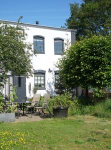 ein weißes Haus mit Stühlen und einem Tisch im Hof in der Unterkunft Sfeervolle bovenwoning uit 1916 met 2 slaapkamers in Hooghalen