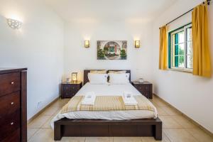 a bedroom with a large bed and two windows at Falésia Beach Villa by The Portuguese Butler in Olhos de Água +40 photos