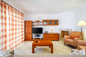 a living room with a couch and a tv at Falésia Beach Villa by The Portuguese Butler in Olhos de Água