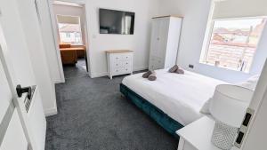 ein weißes Schlafzimmer mit einem Bett und einem Fenster in der Unterkunft Coastal Hideaway by Seaside Llandudno in Llandudno