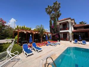 a swimming pool with lounge chairs and a house at Palma Rosa Hotel in Kemer