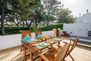 a wooden table and chairs on a patio at Falésia Beach Villa by The Portuguese Butler in Olhos de Água