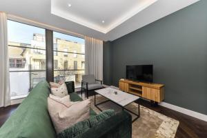 a living room with a green couch and a television at North Kensington - Portobello by Viridian Apartments in London