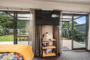 a bedroom with a bed and a flat screen tv at Birdsong - Turangi Holiday Unit in Turangi