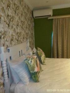 Un dormitorio con una cama blanca con almohadas. en Mkhandi Self Catering en Durban