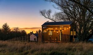 una casita con luces en un campo en The Minimalist Tiny House, 