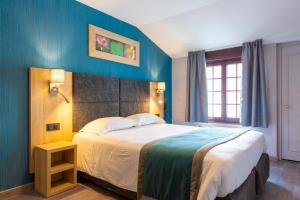 a bedroom with a large bed with a blue wall at Hôtel L'Escale - Piscine & SPA in Escalles