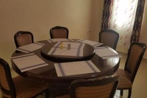a dining room table with chairs and a wooden table with napkins at La petals hideaway house Machakos in Machakos