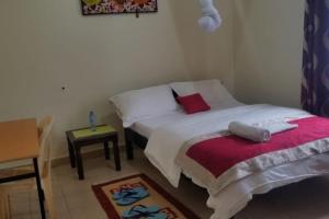 ein kleines Schlafzimmer mit einem Bett und einem Tisch in der Unterkunft La petals hideaway house Machakos in Machakos