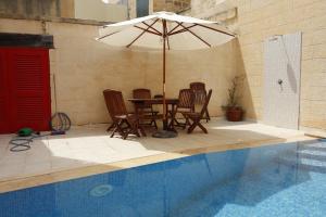 a table and chairs with an umbrella next to a pool at Rosehill B&B in Xagħra