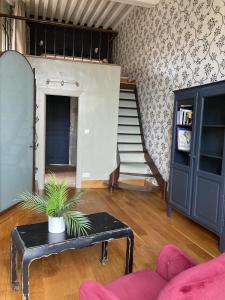 ein Wohnzimmer mit einem Sofa, einem Tisch und einer Treppe in der Unterkunft Les Ordalies in Castelnaudary
