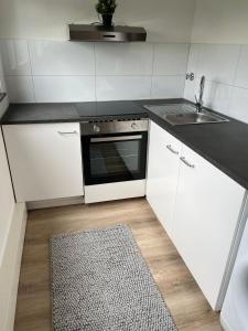 a white kitchen with a sink and a stove at ND Hotels & Studio Apartment Mülheim in Mülheim an der Ruhr
