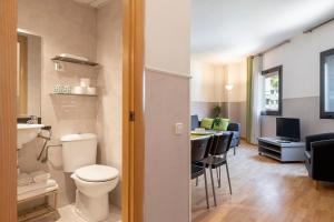 a bathroom with a toilet and a kitchen with a table at Apartments Sata Park Guell Area in Barcelona