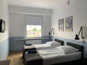 two beds in a room with a window at Premium Hostel & Bistro in Mielec