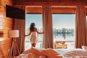 Eine Frau, die in einem Schlafzimmer steht und aus dem Fenster schaut. in der Unterkunft Plana Resort & SPA in Castel Volturno