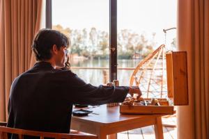 Un uomo seduto a un tavolo davanti a una finestra di Plana Resort & SPA a Castel Volturno