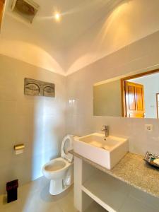 uma casa de banho branca com um lavatório e um WC em Villa Seruni Lovina em Lovina