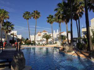 a swimming pool with palm trees in a resort at La Perla Azul - Terraza panorámica al Sol in Roquetas de Mar