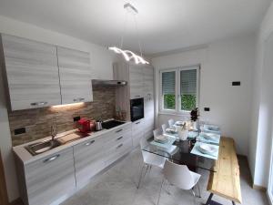 a kitchen with white cabinets and a table with chairs at Tirano Express Luxury Appartamento rialzato con vista giardino, barbecue e comfort esclusivo in Tirano