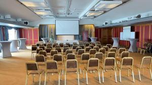 une grande salle avec une salle de conférence dotée de chaises et d'un écran dans l'établissement Storlien Högfjällshotell AB, à Storlien
