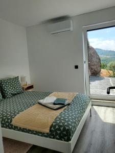 um quarto com uma cama com uma janela grande em Douro Mesio Guest House em Resende