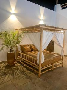 Magnifique villa sans vis-à-vis • Marrakech في مراكش: سرير فيه مظله في غرفه فيها نبات