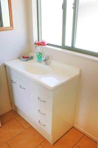 baño con lavabo blanco y ventana en Paparei Beachfront Bungalows, Aitutaki en Arutanga