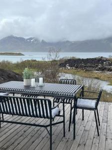 a table and chairs on a deck with a view of the water at Luksushytte med Jacuzzi, Summer&Winter Retreat in Lyngværet