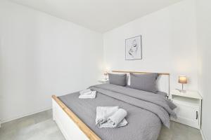 biała sypialnia z łóżkiem z szarą pościelą i poduszkami w obiekcie Ferienhaus Bärenbrunnen w mieście Bernkastel-Kues