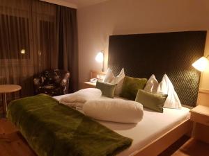 a hotel room with a large bed with green and white pillows at Sport & Familienhotel Bärenwirt in Aich