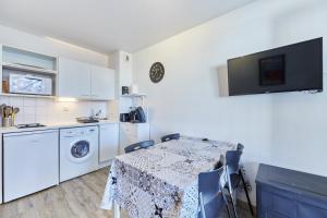 eine Küche mit einem Tisch und eine Küche mit weißen Geräten in der Unterkunft Sea Blue - Appt à 1km de la plage in Villers-sur-Mer