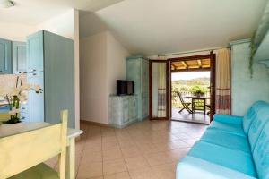 uma sala de estar com um sofá azul e uma cozinha em Museddu Beach Residence em Cardedu