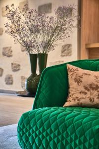 a green couch with a pillow and a vase with flowers at Falkensteiner Genuss & Wohlfühlhotel Mühlviertel in Bad Leonfelden