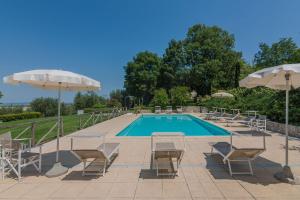 una piscina con sillas, mesas y sombrillas en Villa Il Fiore e la Farfalla 14 en Pesaro