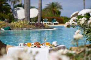 a table with food and drinks next to a swimming pool at Hotel Porto Mare - PortoBay in Funchal