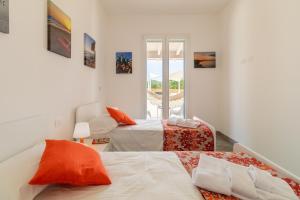 two beds in a white room with a window at Villa melograno in Ispica