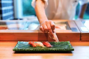 a person is preparing sushi on a plate at The Prince Park Tower Tokyo - Preferred Hotels & Resorts, LVX Collection in Tokyo