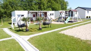a park with a playground with palm trees and swings at Domki Letniskowe BŁĘKIT in Gąski