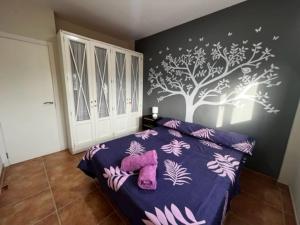 Un dormitorio con una cama morada con un árbol en la pared en Adosado Estany, en Cullera